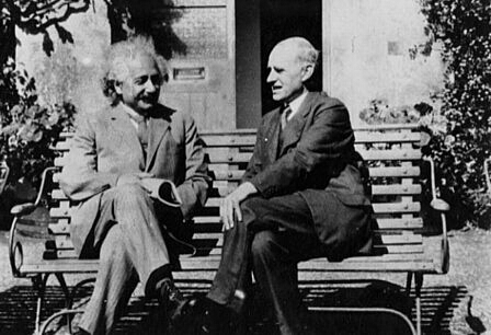 Einstein e Eddington em Cambridge, sentados em um banco de praça conversando