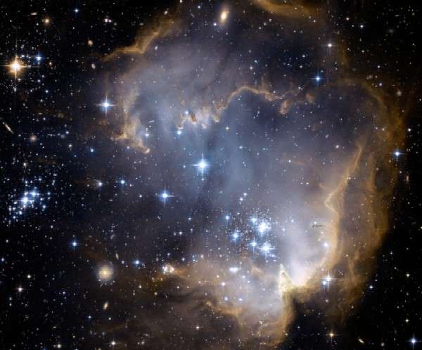 aglomerado estelar ngc602 com estrelas azuis no centro e a nuvem d poeira em volta com outras estrelas a sua volta