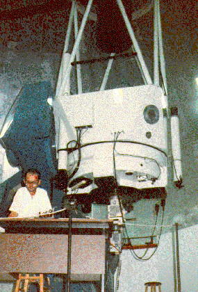 homem sentado a frente do telescopio do LNA em parado na vertical